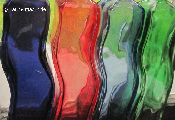 Curving, coloured glass bottles in a window