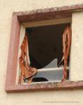 Broken window and torn curtain
