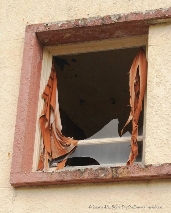 Broken window and torn curtain