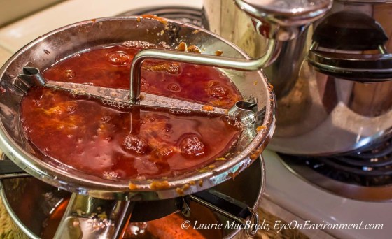 hot plums in a food mill on top of a stove