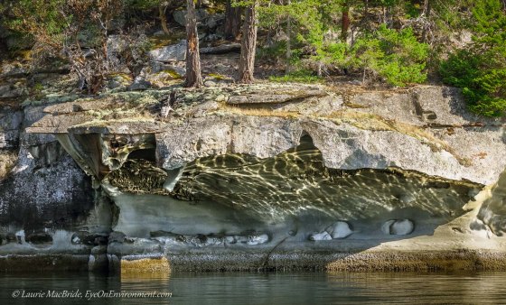 Network of light reflected onto wall of sandstone cave over the water